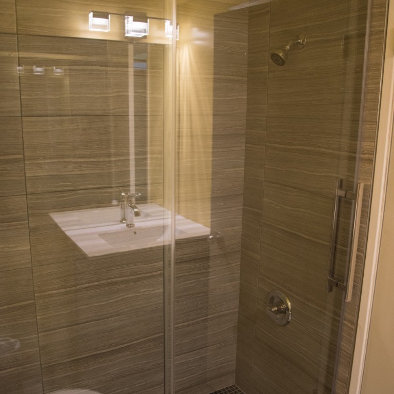 Walk-in shower with glass door and stone-tile walls