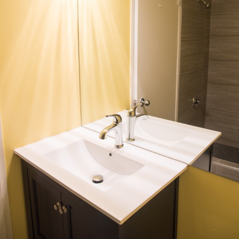 Bathroom vanity with mirror, chrome faucet, and overhead lighting
