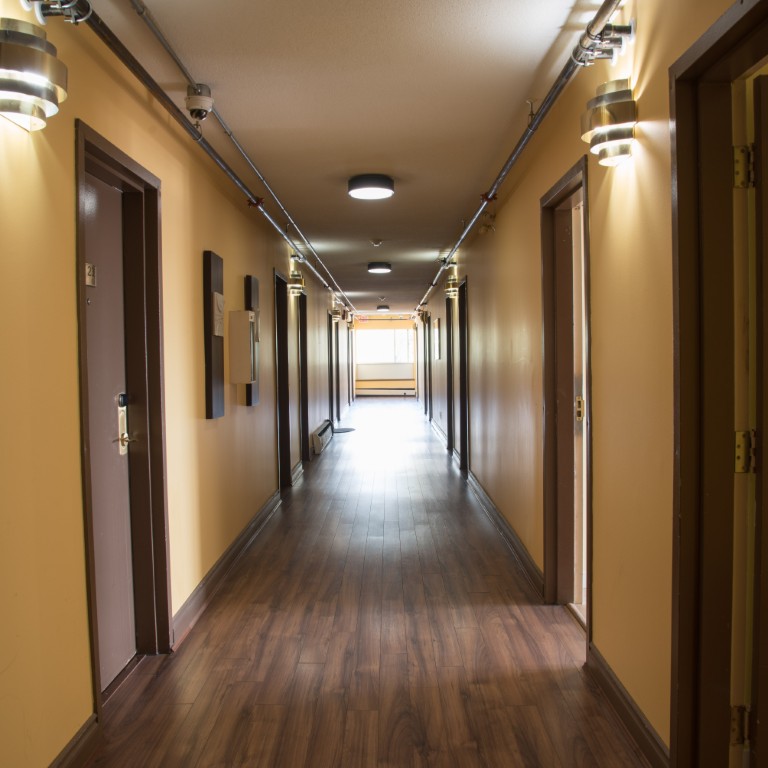 Studio corridor with track lighting and wood-grain flooring leading to private entrances